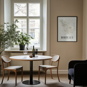 Bordeaux Wine Map poster by Corkframes framed on a wall beside a window, with a small dining table and wine glasses