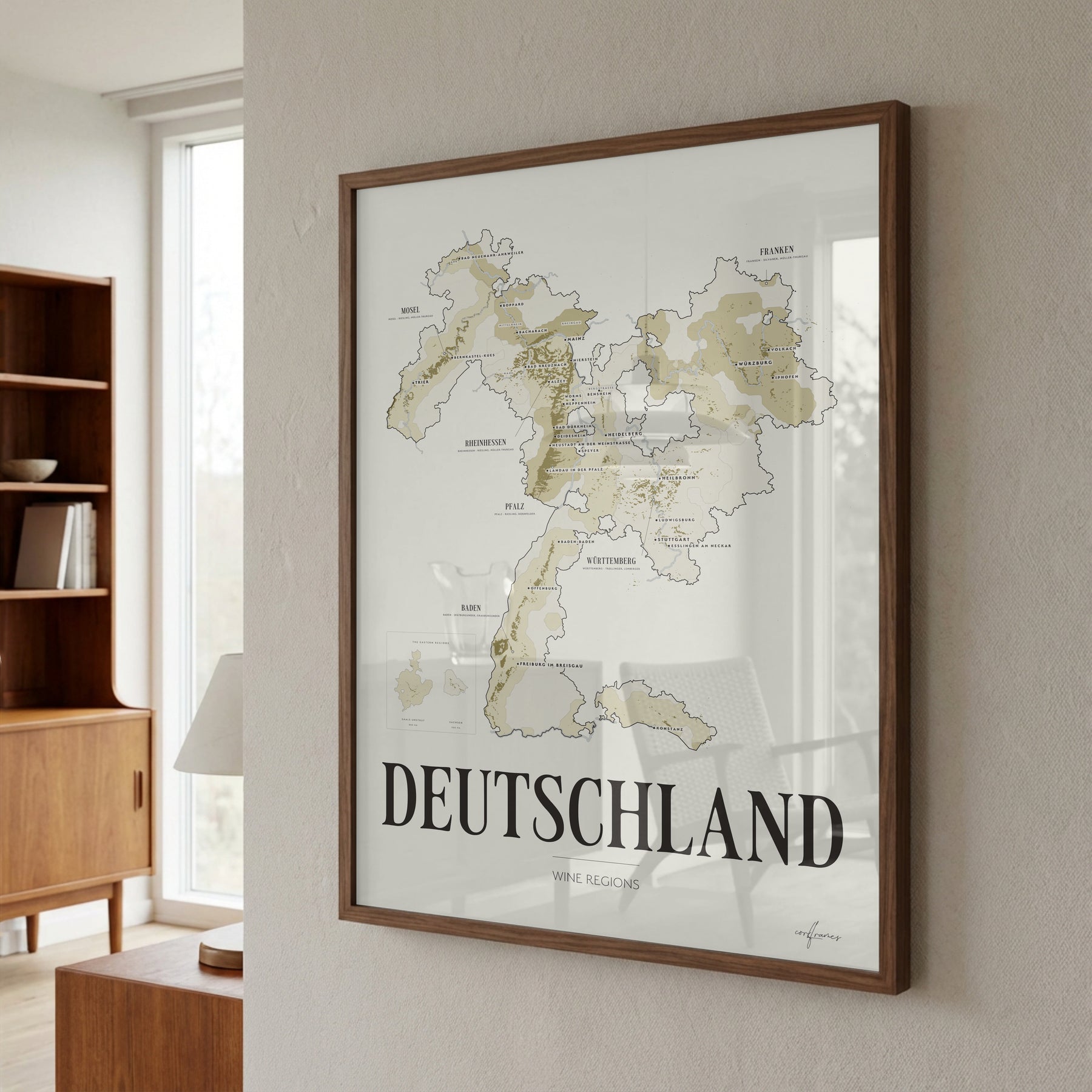 Deutschland Wine Map poster by Corkframes in a walnut frame on a plaster wall beside a bookcase and a sunlit window