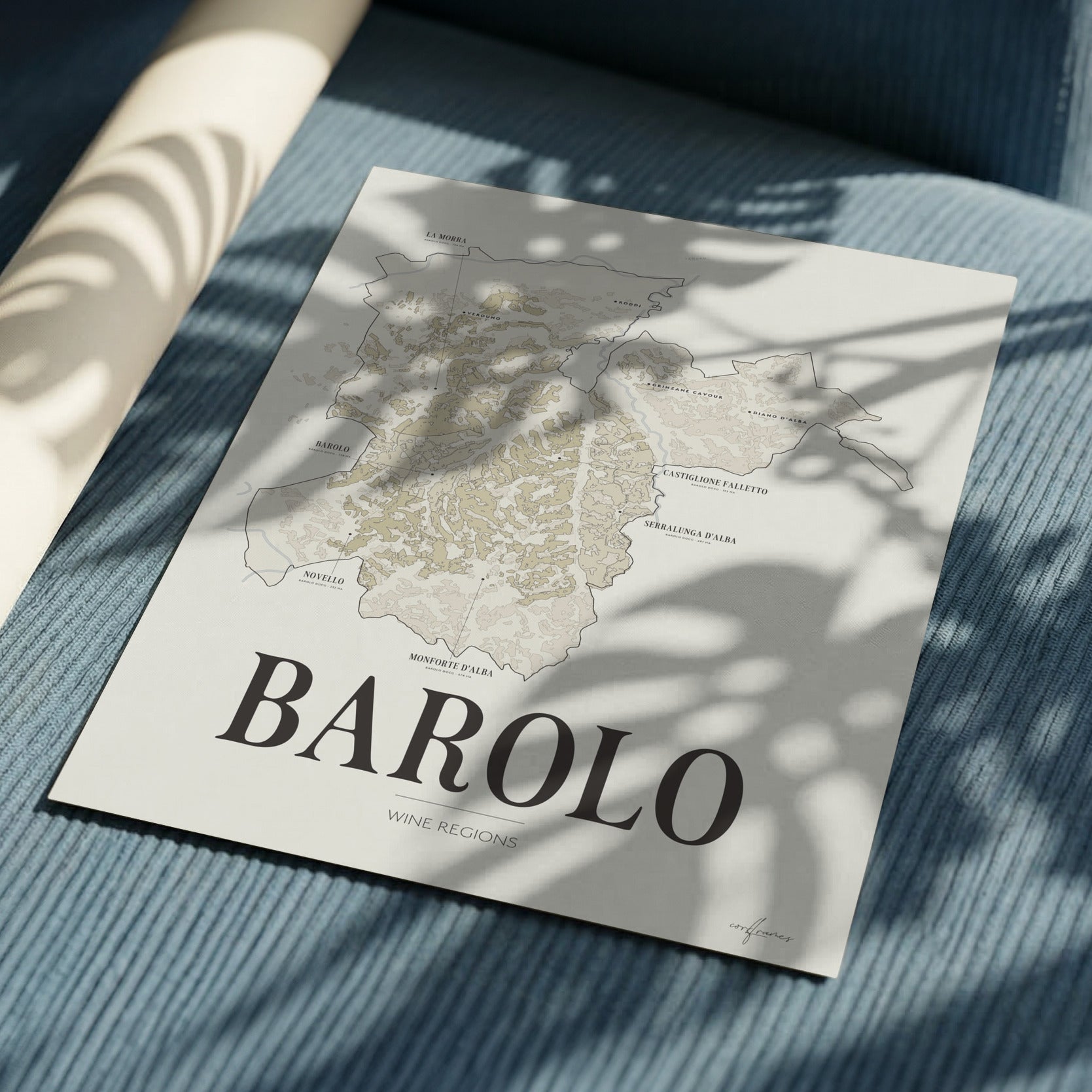 Barolo Wine Map poster by Corkframes lying on blue corduroy fabric in dappled sunlight