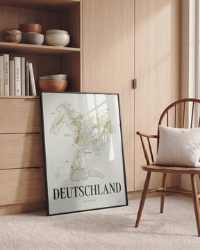 Deutschland Wine Map poster by Corkframes in a black frame leaning against a wooden cabinet beside a spindle chair