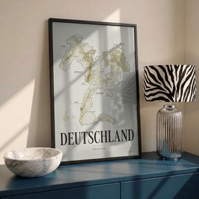 Deutschland Wine Map poster by Corkframes in a black frame on a blue sideboard with a marble bowl and a striped lamp