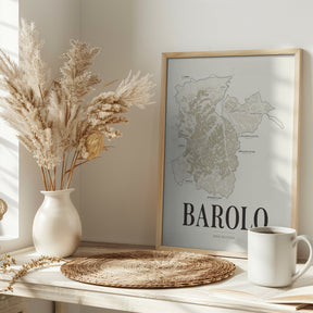 Barolo Wine Map poster by Corkframes in a light wood frame on a console with dried pampas grass and a mug