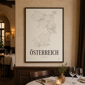 Österreich Wine Map poster by Corkframes framed on a plaster wall in a restaurant, above a laid table with wine glasses and a candle