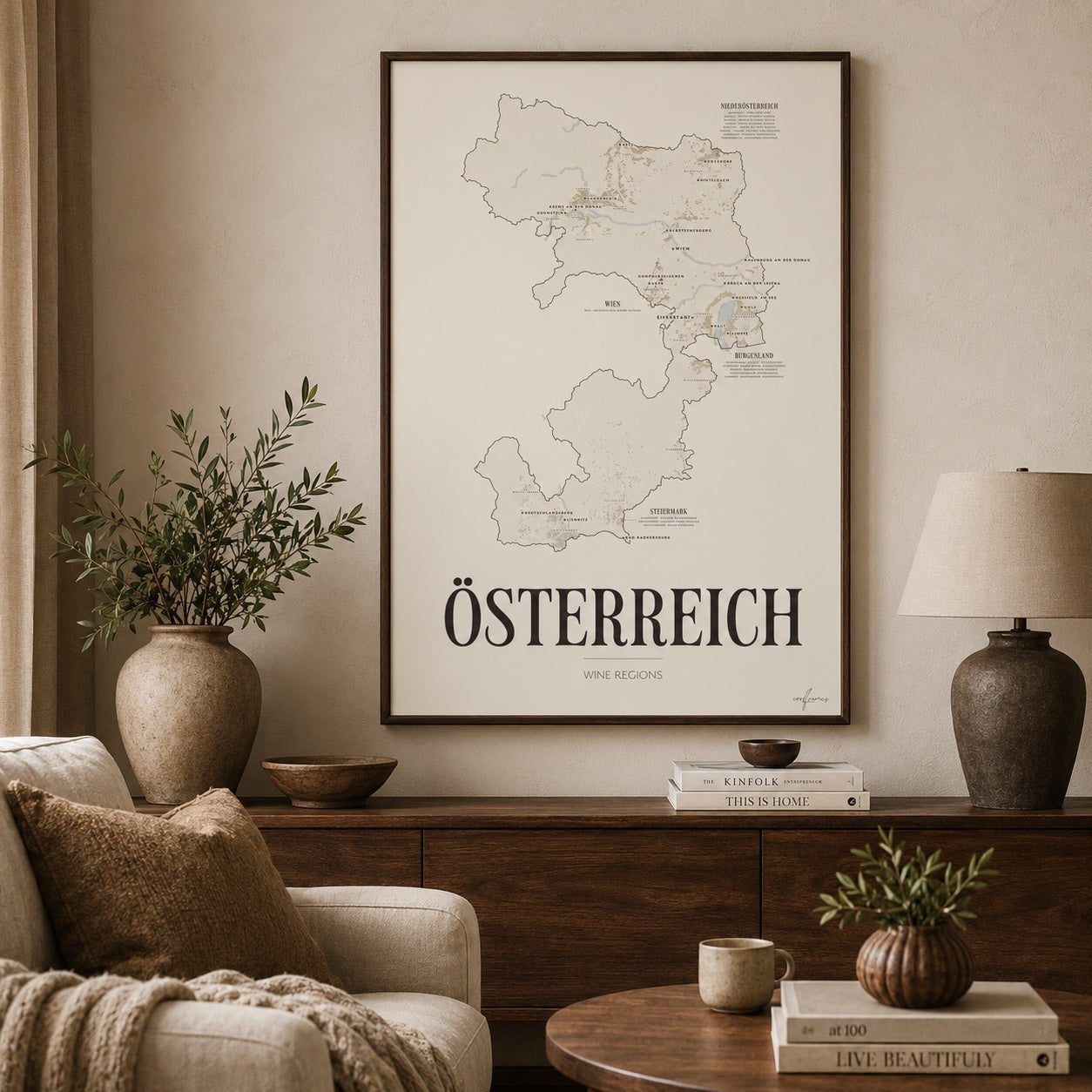 Österreich Wine Map poster by Corkframes framed above a sideboard in a living room, with an olive branch in a stone vase and a ceramic lamp